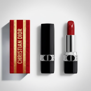 Christian Dior lipstick shown with its red and gold box, the closed black lipstick tube, and the open lipstick with the red bullet and silver casing, arranged on a light gray background.