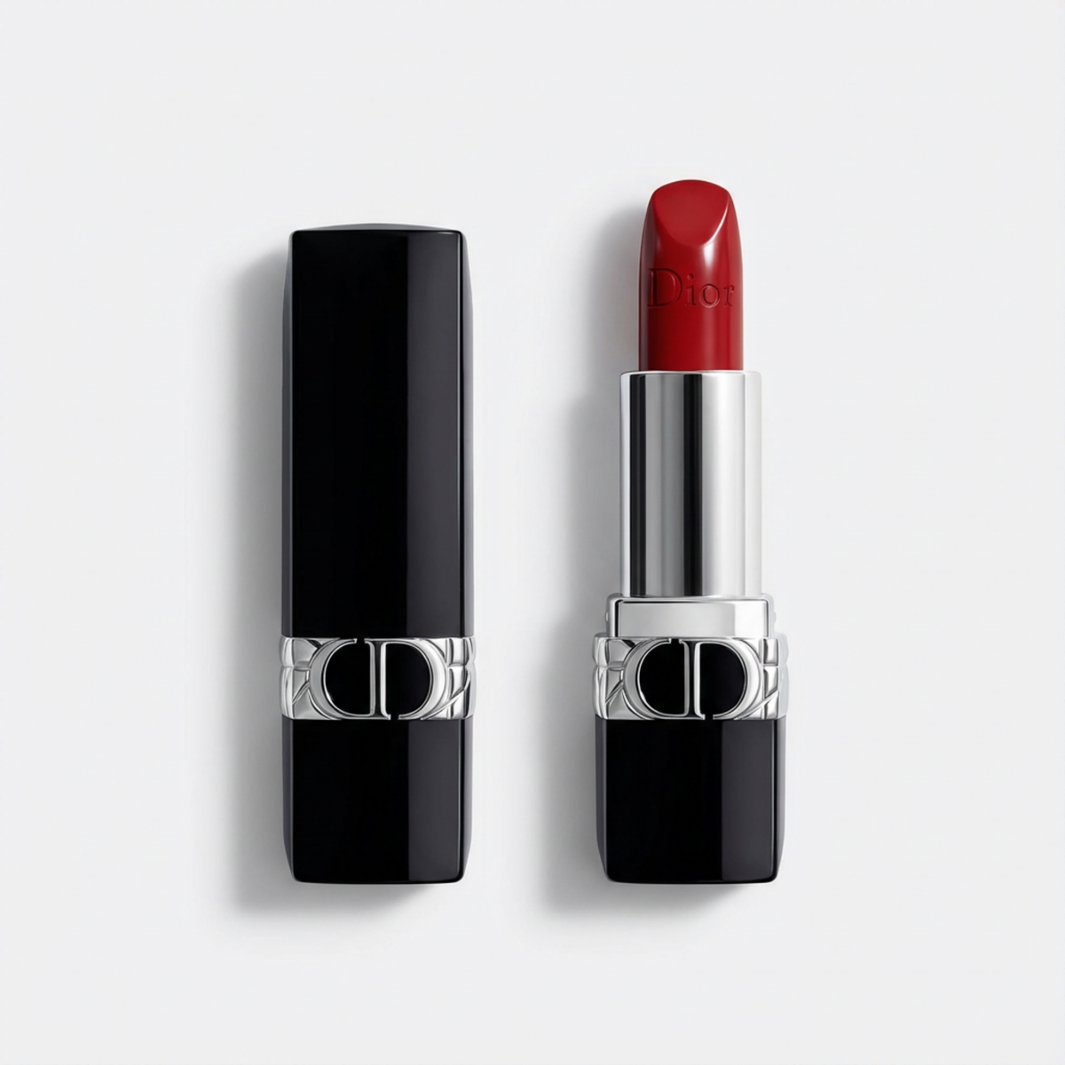 Dior lipstick shown open next to its black cap on a light gray background. The lipstick bullet is a deep red shade, and the tube features a silver collar with the Dior logo.