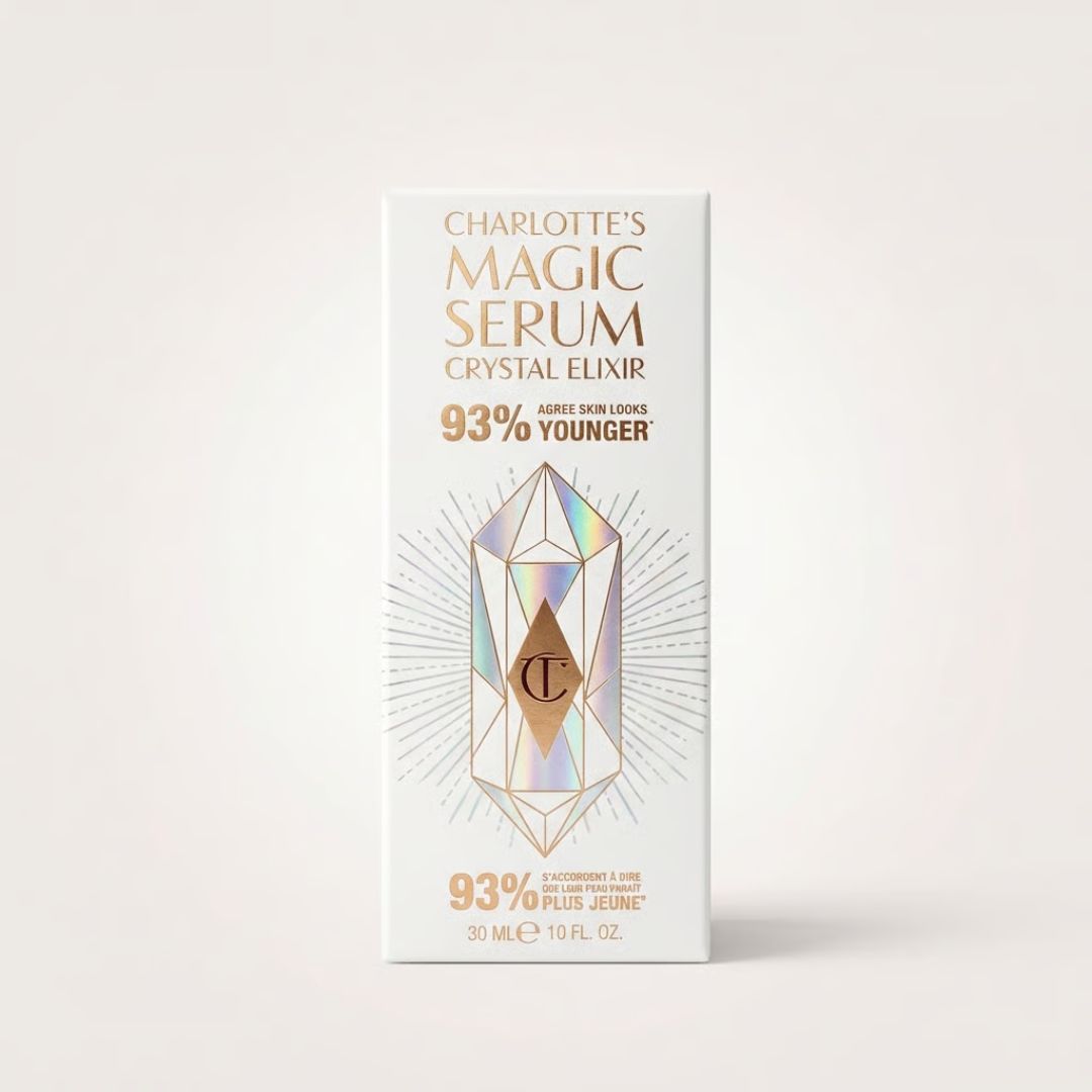 Charlotte's Magic Serum Crystal Elixir skincare box packaging, featuring a white background with gold lettering and a central iridescent crystal graphic.