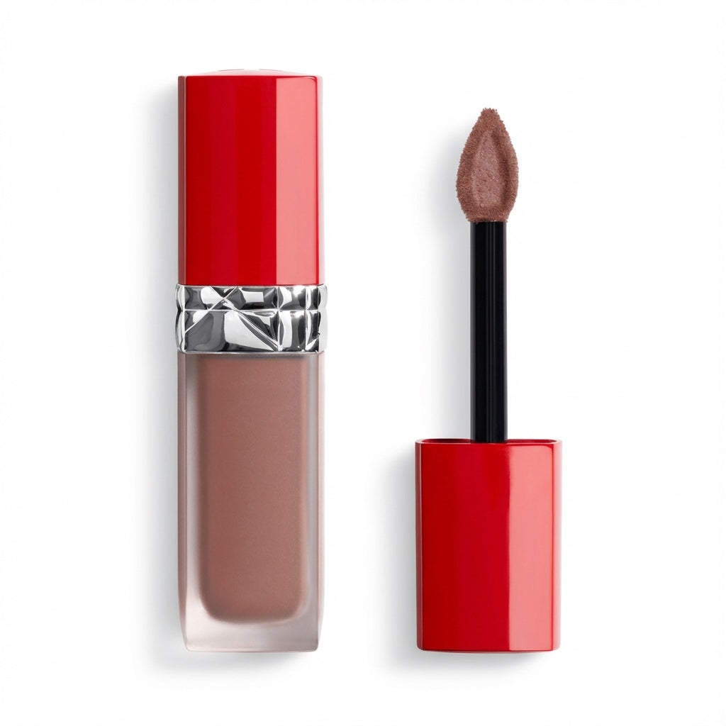 A liquid lipstick in a clear rectangular tube showing a nude brown shade, with a bright red cap and silver band. The applicator wand with a pointed doe-foot tip is shown beside it on a clean white background.