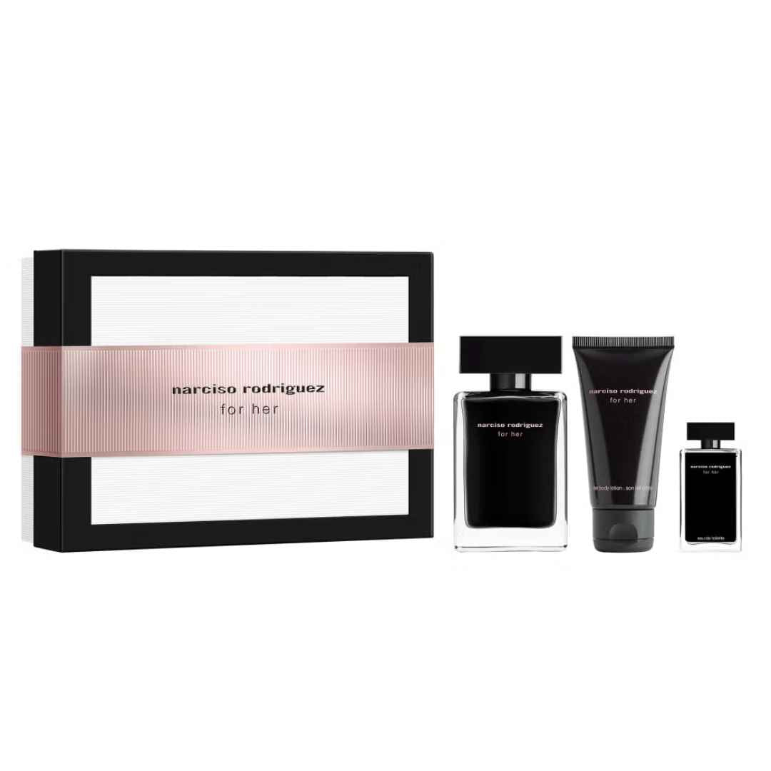 Narciso Rodriguez for her fragrance gift set on a white background, featuring a black and white box with a pink band, a black perfume bottle, a black body lotion tube, and a small black spray bottle.