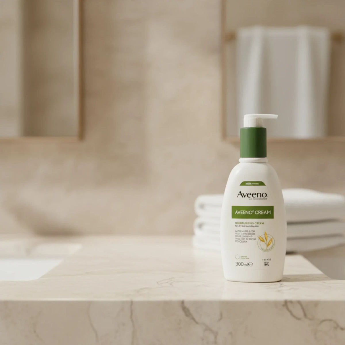 Aveeno Avenym Cream lotion bottle with a green pump, standing on a marble bathroom counter with a softly blurred background.