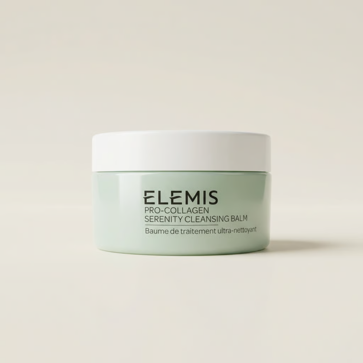 Elemis Pro-Collagen Serenity Cleansing Balm in a light mint green jar with a white lid, centered on a warm off-white background.